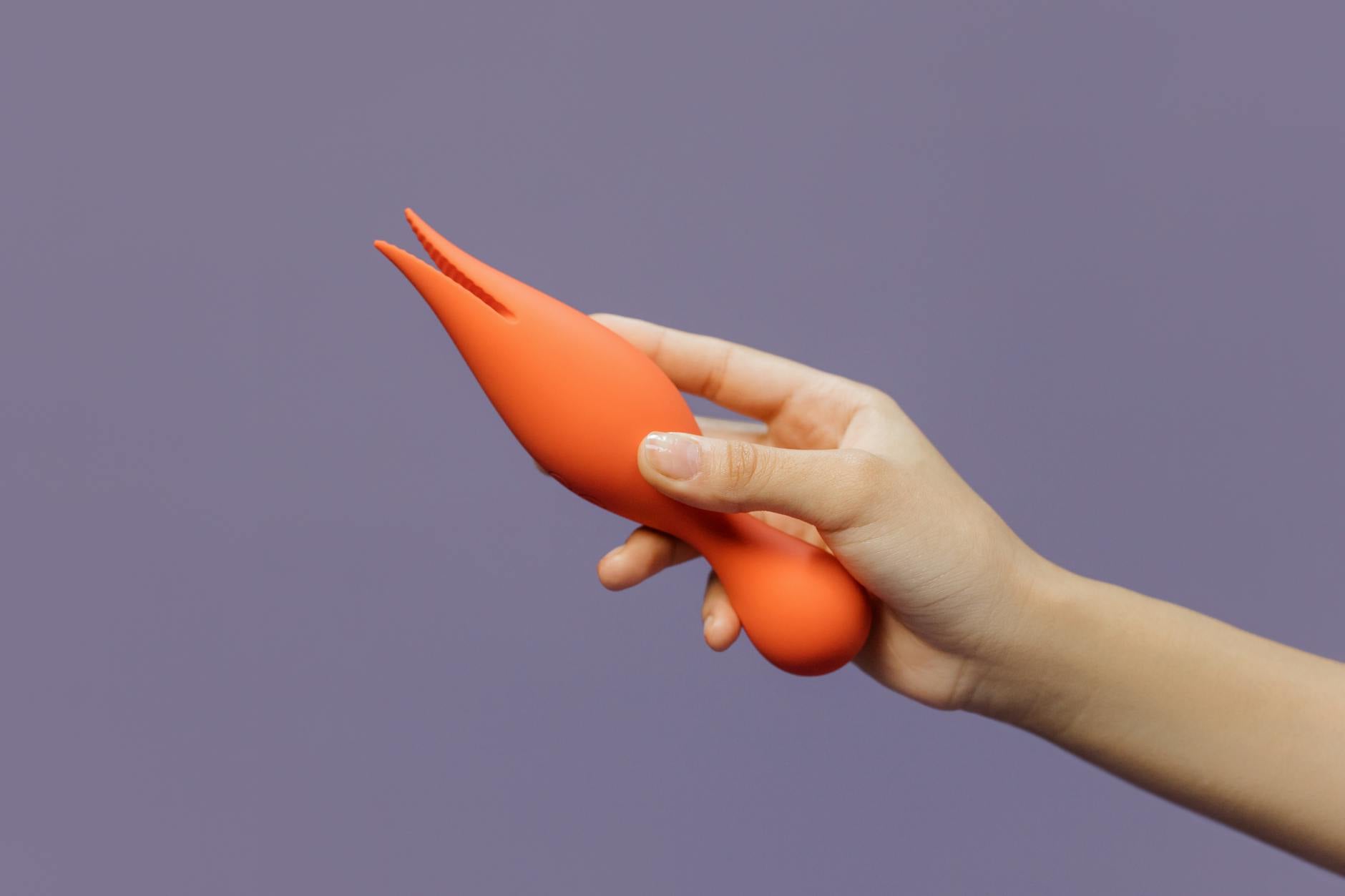 A hand holding a lemon-colored vibrator against a soft purple backdrop, symbolizing gentle postpartum pleasure recovery