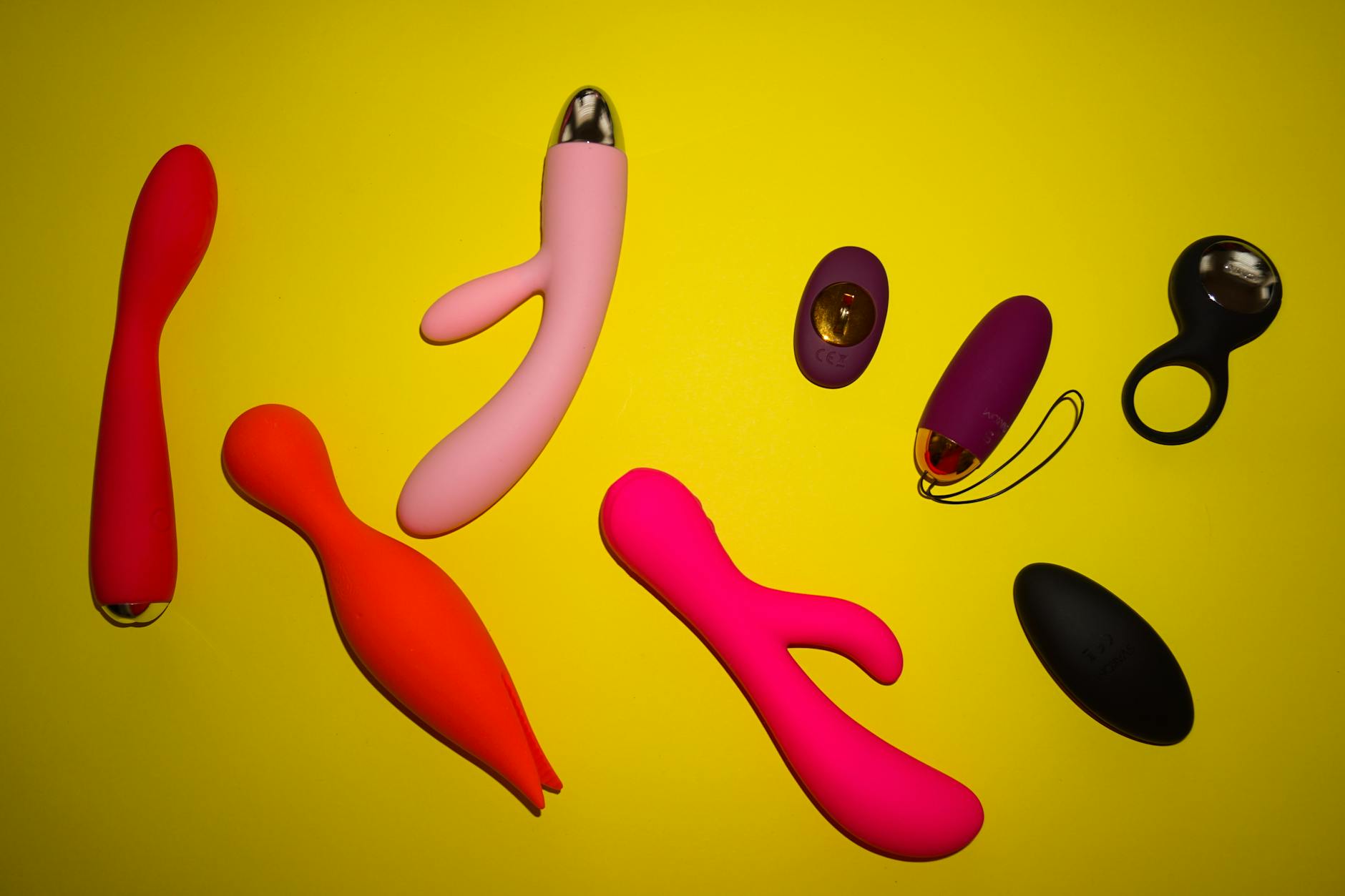 Close-up of a hand holding an orange vibrator against a minimalistic purple backdrop